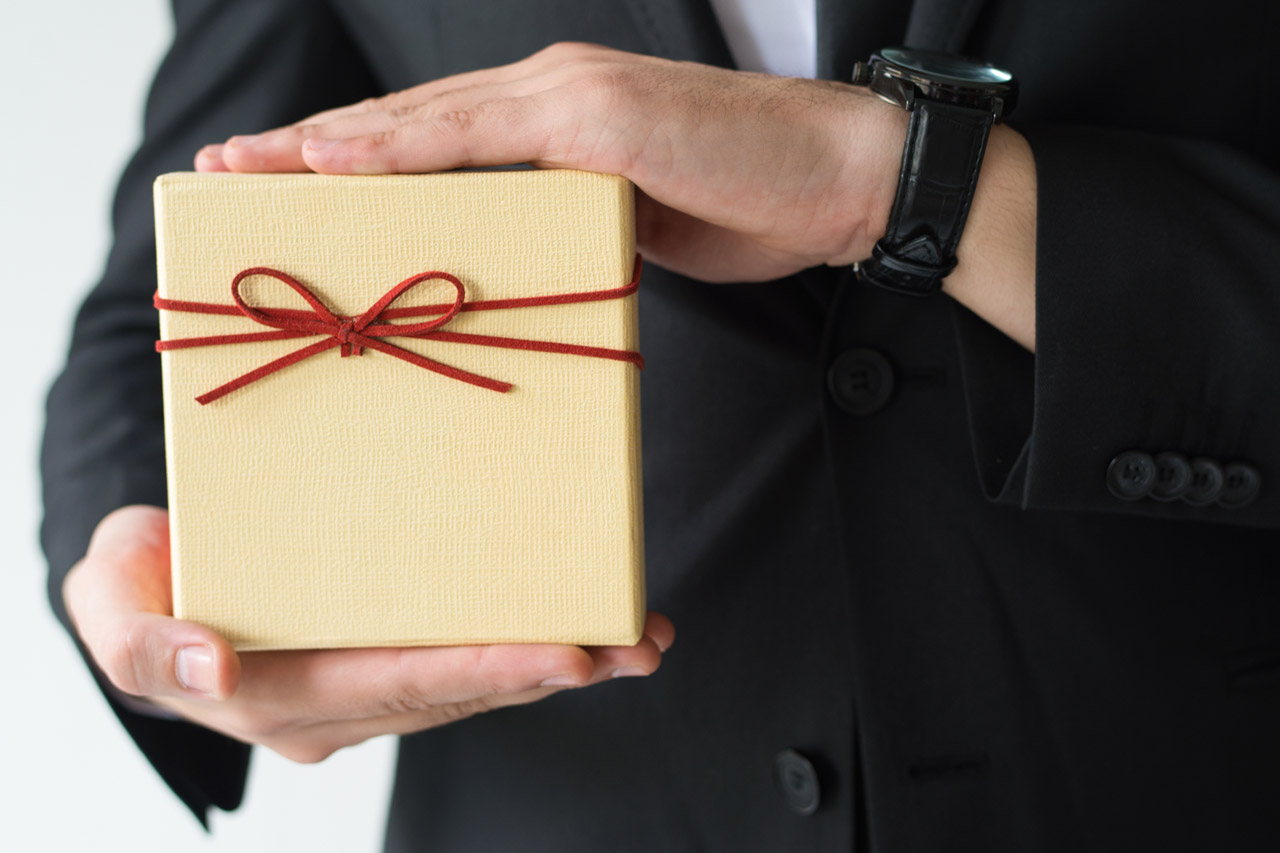 Una persona con vestida de traje con un regalo en las manos